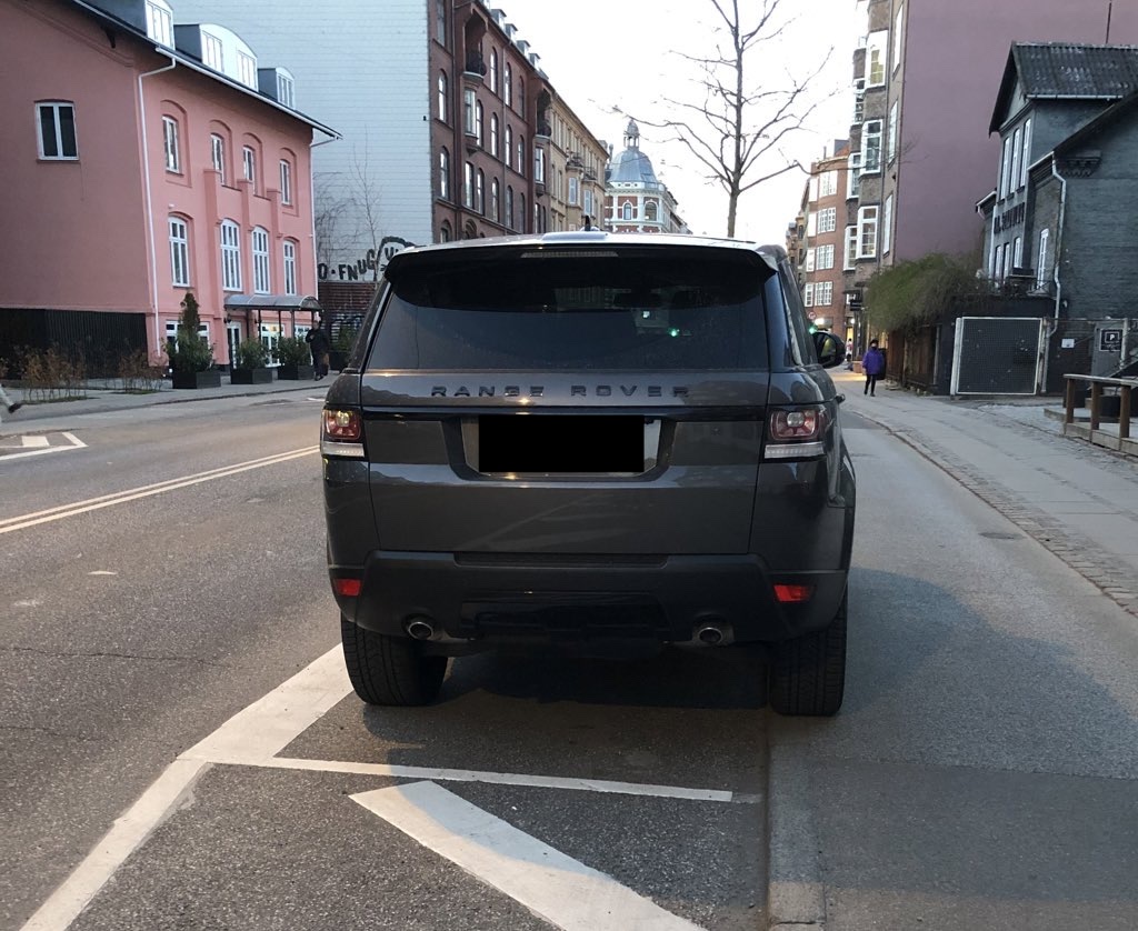 Bil parkeret med det ene hjulsæt på cykelstien